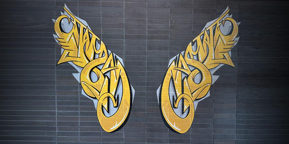 Artistic interpretation of wings on a black brick wall inside of the Cal State LA student services building.