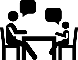 Silhouette of two people sitting at a table having a conversation.