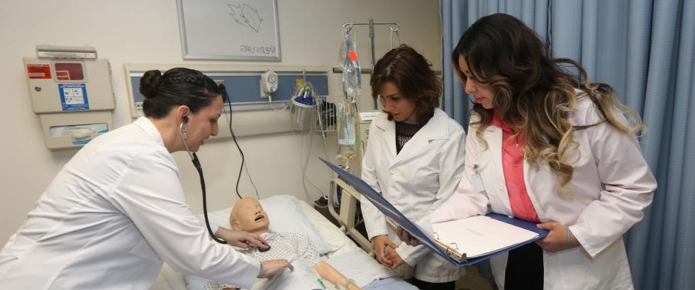 Master's students inspect a dummy patient in the Simulation Lab.