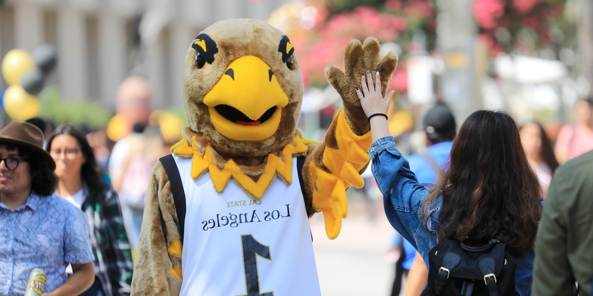 Eddie the Golden Eagle high-giving a student on the Main Walkway.