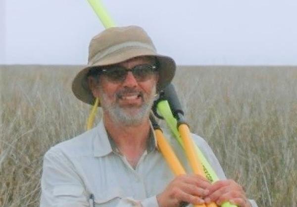 Professor Beland in the field holding measurement instruments. 