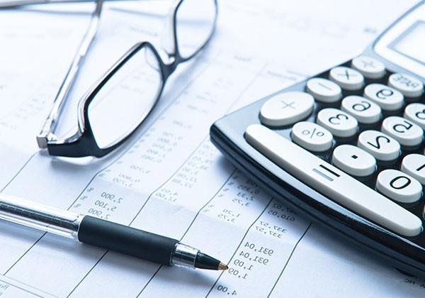 calculator and pen with glasses on desk