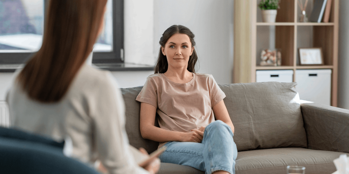 Women sits on sofa. 另一个女人坐在她对面.