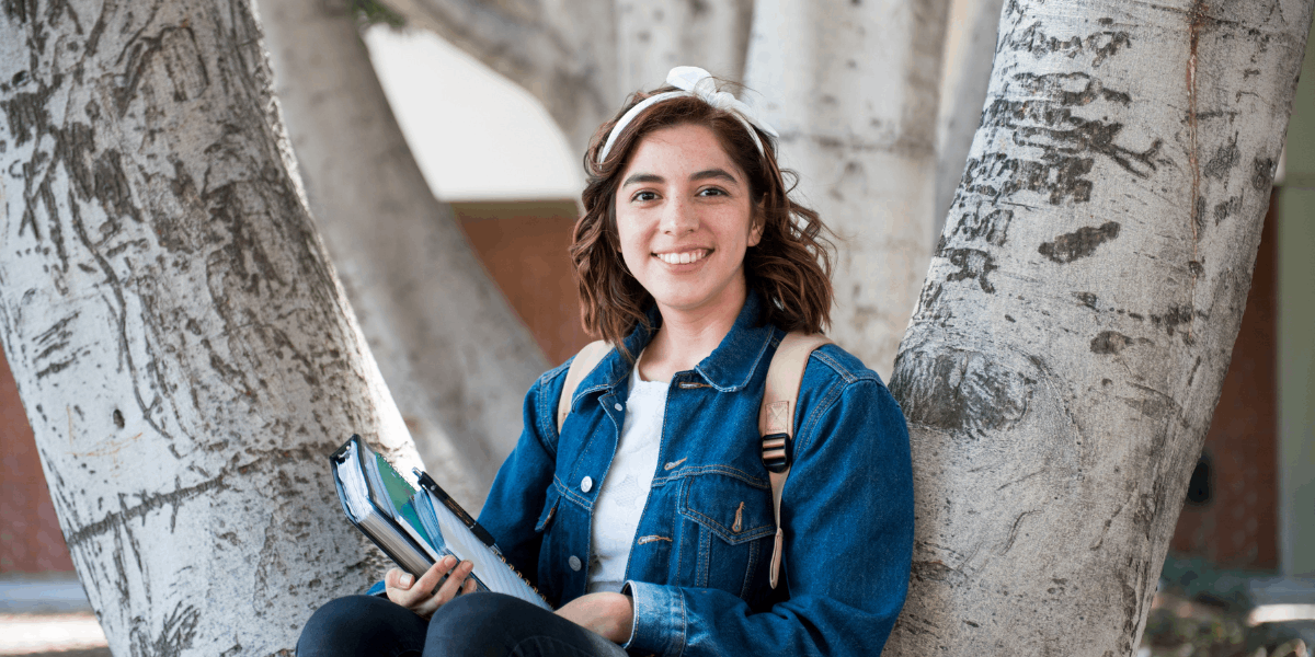 Female student with backpack and holding books.