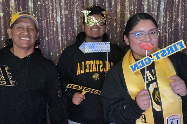 Three people holding up props and smiling.