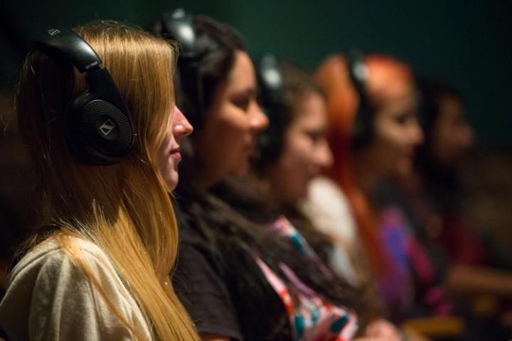 A seated row of students in an audio production class, each wearing headphones.