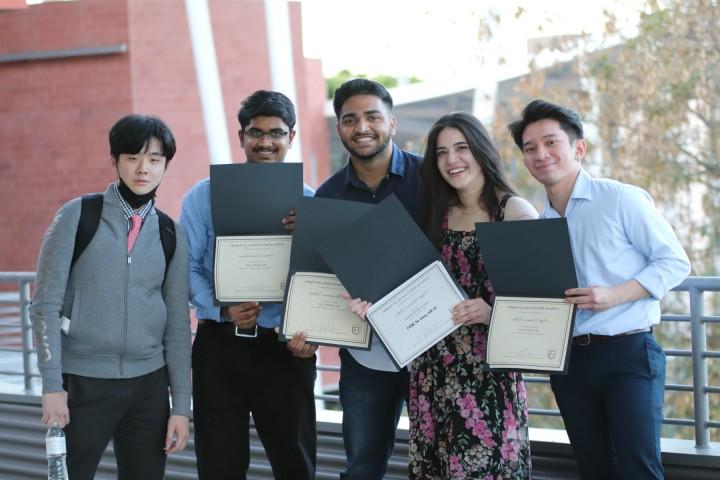 students holding certificates smile