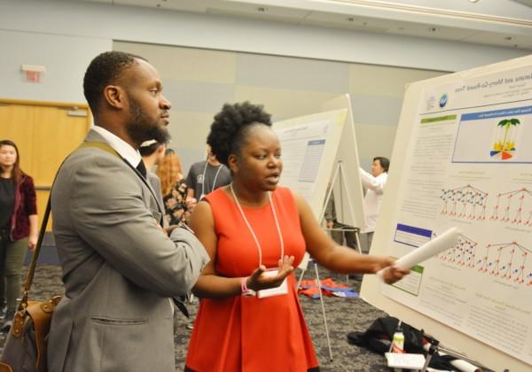 student discussing her poster presentation with attendee