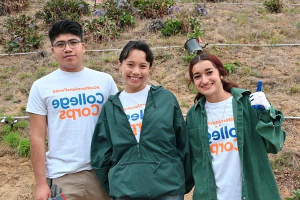 Three fellows posing in front of hill 