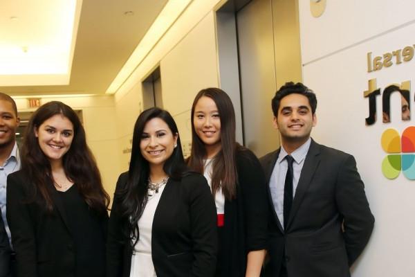 Group of Cal State LA students in business attire standing grouped in front of the NBC Universal Talent Lab sign. 