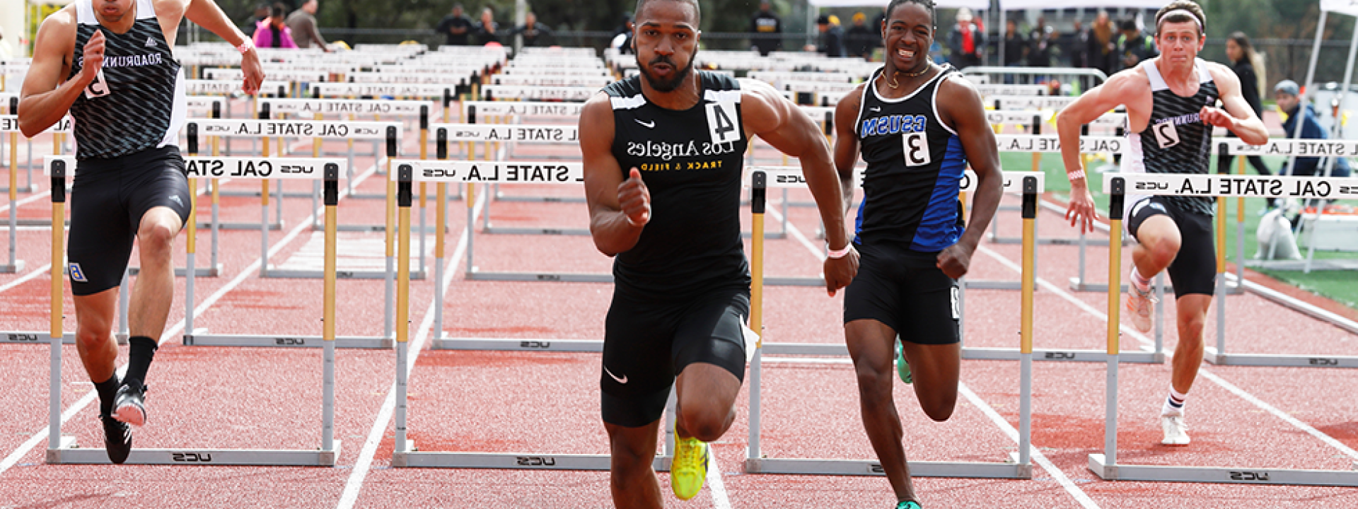 Image of a Cal State LA track star leading a hurdle race. 