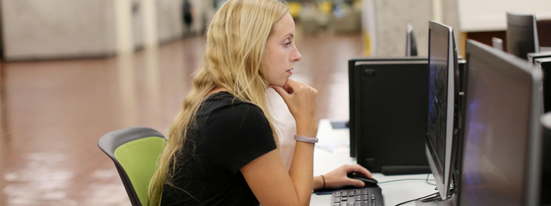 Image of female student in University Library using a computer station. 